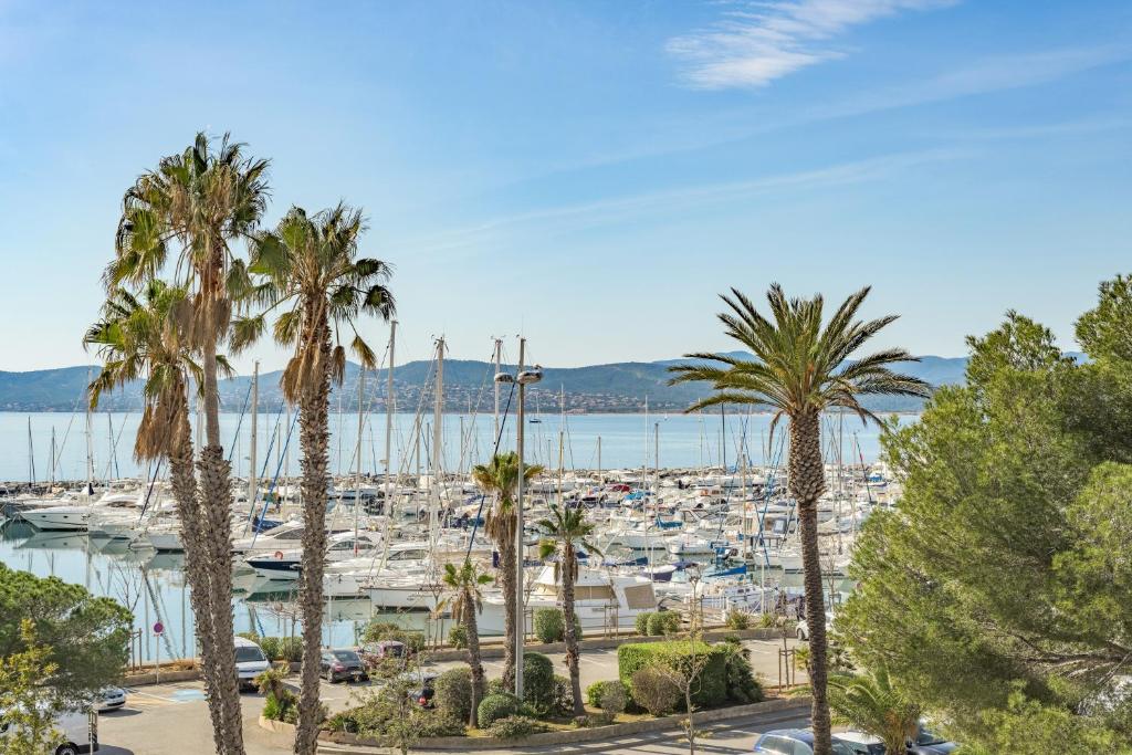 un port de plaisance avec des palmiers et des bateaux dans l'eau dans l'établissement Appartement Port Santa Lucia - Le Manoir, à Saint-Raphaël