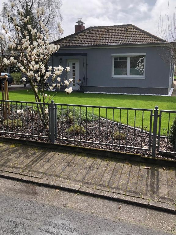 a fence in front of a house with a flowering tree at FeWo Im Grünen in Lilienthal