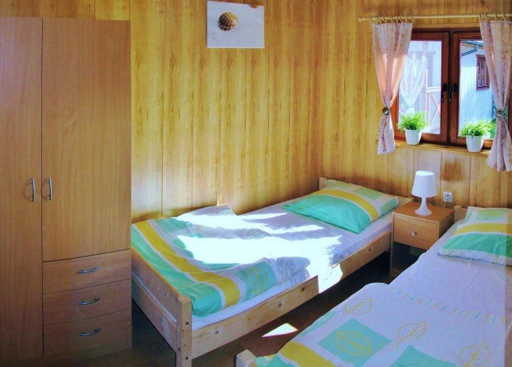 two twin beds in a bedroom with wooden walls at Domki Letniskowe Las Palmas Dąbki in Dąbki