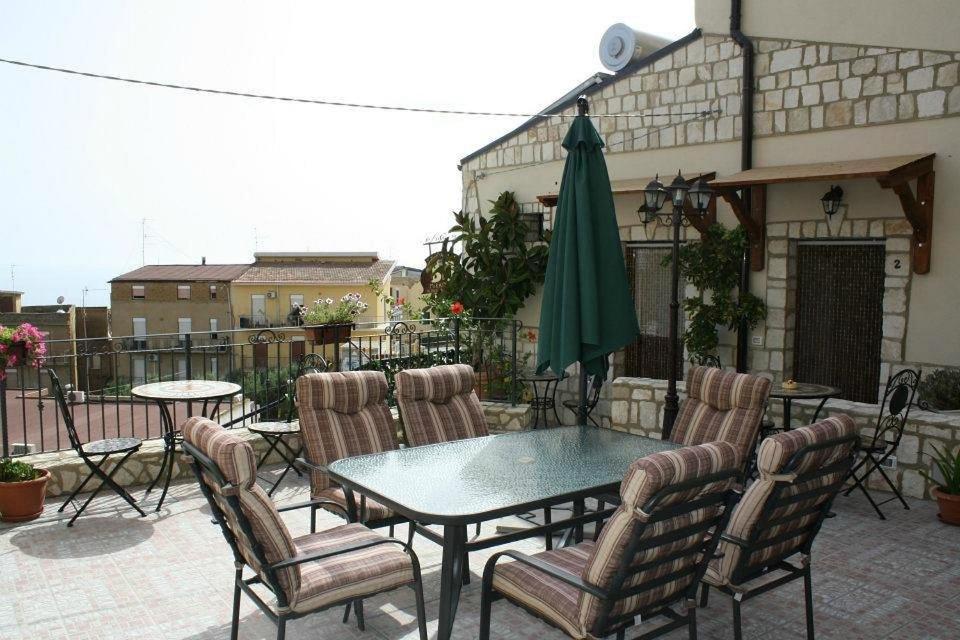 a patio with a table and chairs and a green umbrella at Bed and Breakfast Don Angelo Miramare in Realmonte