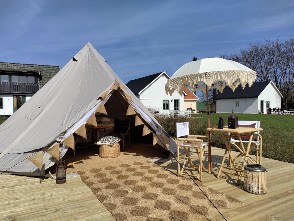 ein großes Zelt mit einem Tisch und einem Sonnenschirm in der Unterkunft Luxury Tent with Restroom and shower, close to the Beach in Ystad