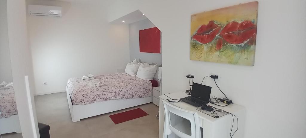 a bedroom with a bed and a desk with a laptop at Mirasole Holiday House in Leggiuno