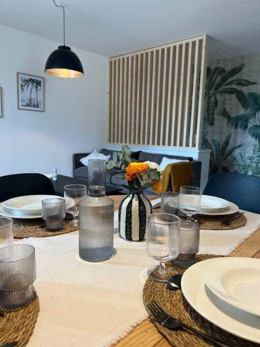 une table de salle à manger avec des assiettes et des verres dessus dans l'établissement Appartement de charme rénové avec garage, à Libourne