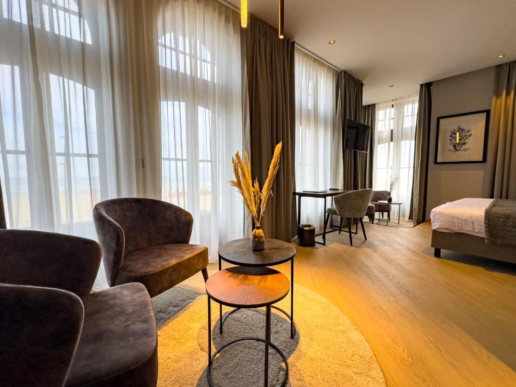 - un salon avec un canapé, des chaises et un lit dans l'établissement Hotel Villa Select, à La Panne