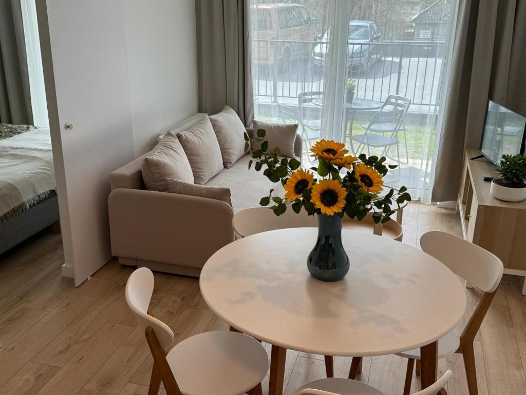 una sala de estar con una mesa con un jarrón de girasoles en Apartament Przystań 1, en Kartuzy