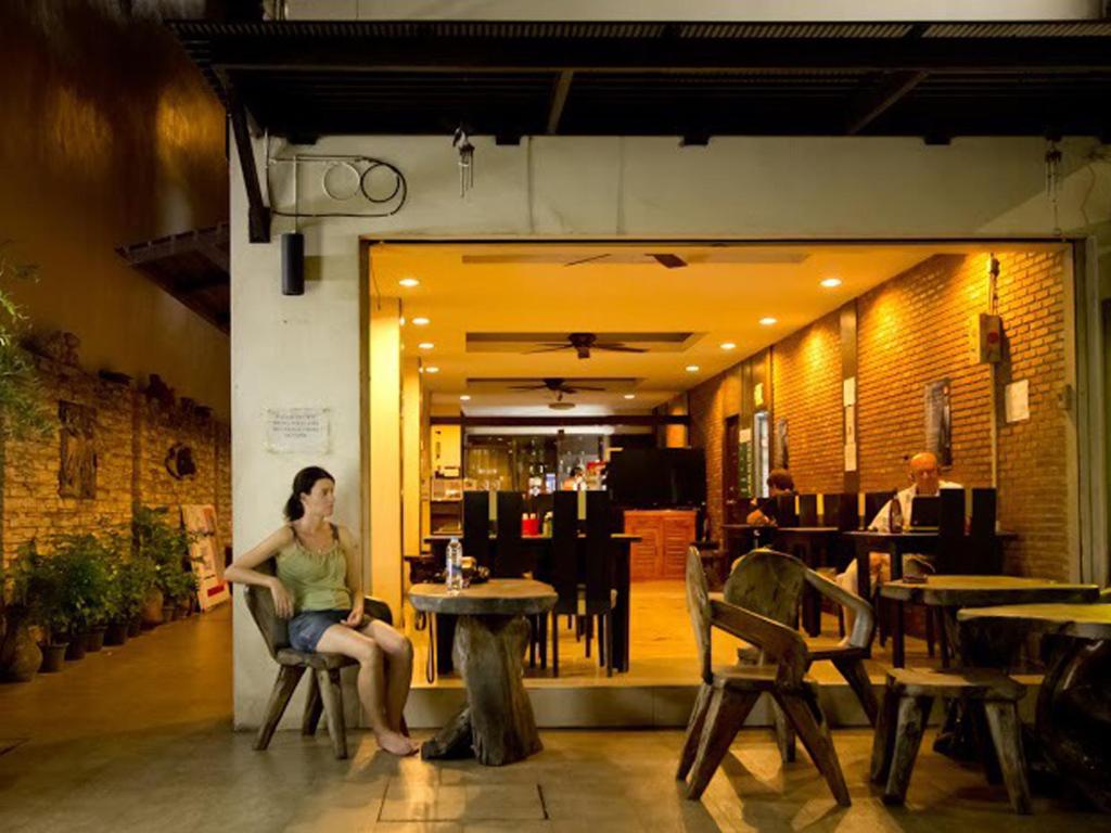 a woman sitting in a chair in a restaurant at At Home Guest House in Bangkok