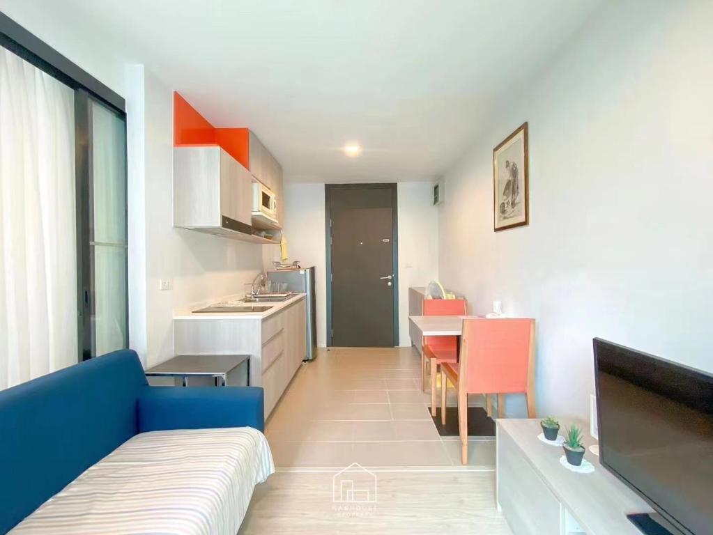 een woonkamer met een blauwe bank en een keuken bij Centrio Condominium Phuket in Ban Rangeng