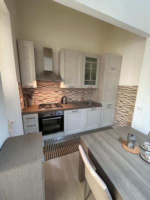 uma cozinha com armários brancos e uma mesa com cadeiras em Appartamento incantevole con patio em Florença
