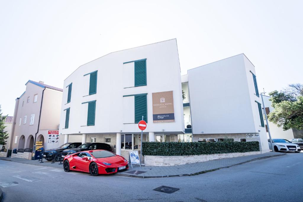 un coche rojo estacionado frente a un edificio en Basilica hotel - made for fun!, en Novalja