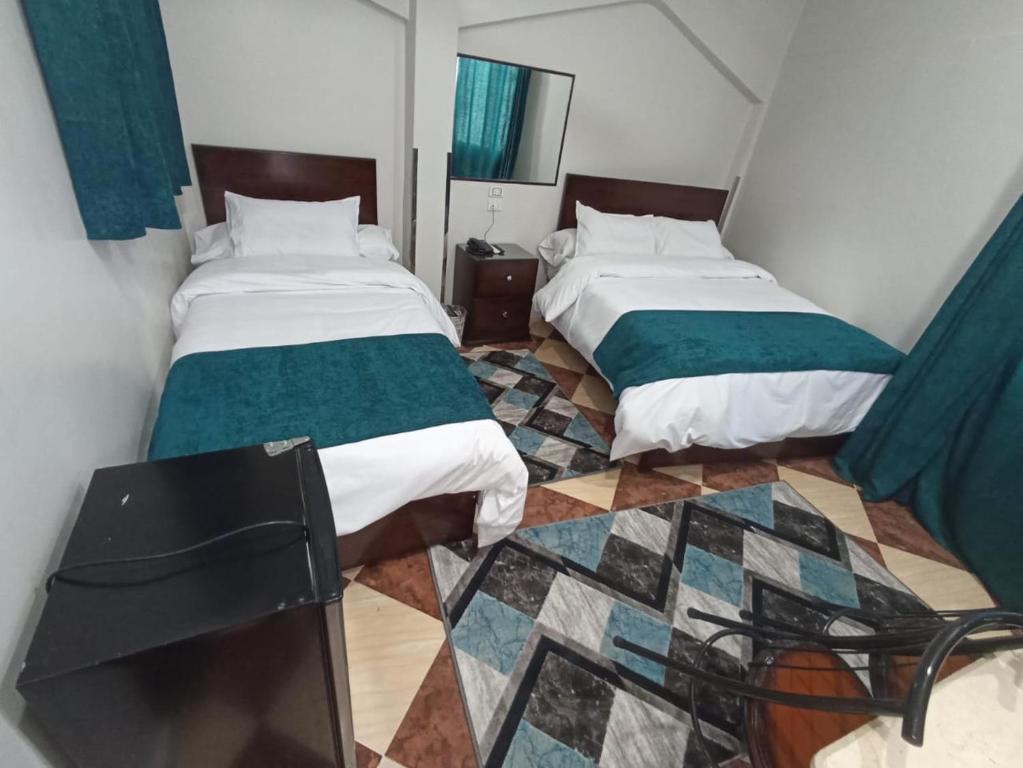 a room with two beds and a tiled floor at Dream Hotel in Qinā