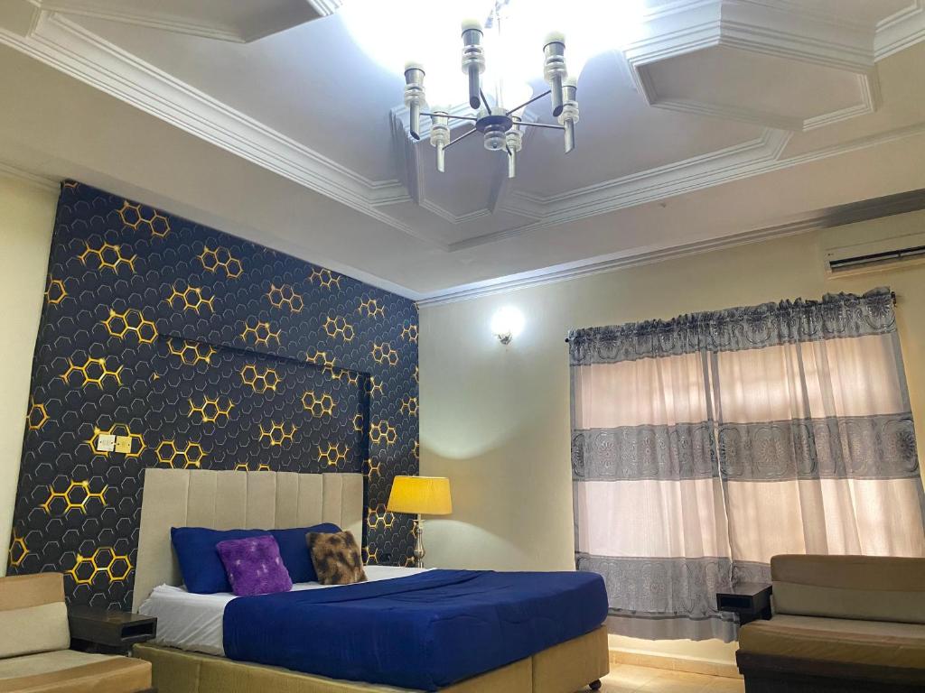 Un dormitorio con una cama azul y una lámpara de araña. en Legends Castle Suites, en Gwarinpa