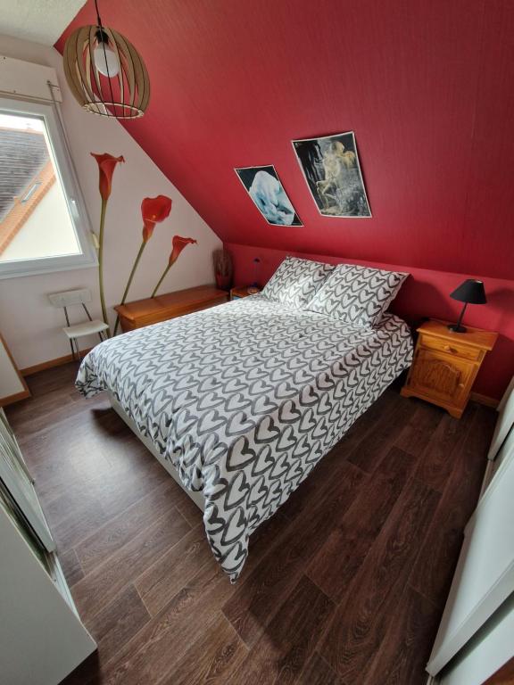ein Schlafzimmer mit einem Bett und einer roten Wand in der Unterkunft Chez Gilles et Isabelle in Cairon