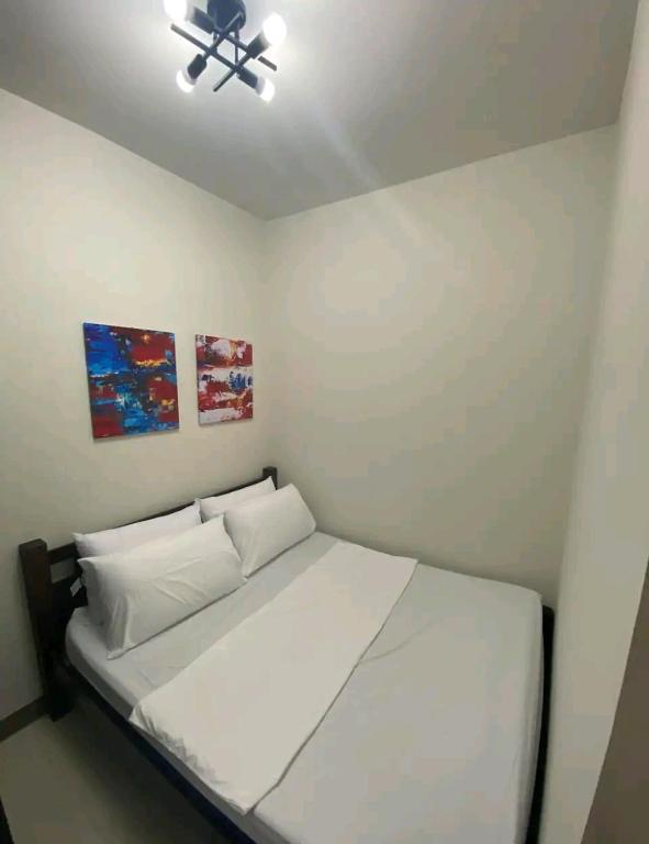 Cette chambre comprend un lit avec des draps blancs et un ventilateur de plafond. dans l'établissement S residences Pasay , near Mall of Asia, à Manille
