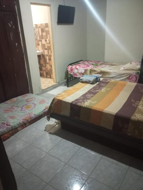 a room with two beds in a room with a doorway at Hostal EL VALLE in Los Algarrobos