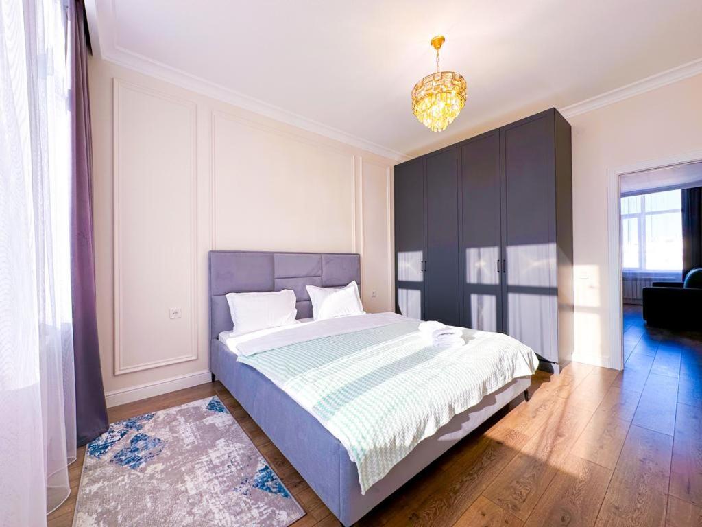 a bedroom with a large bed and a chandelier at Рядом с Экспо Большая 2х комнатная 70м2 и 1-комнатная 45м2 рядом с Экспо in Astana