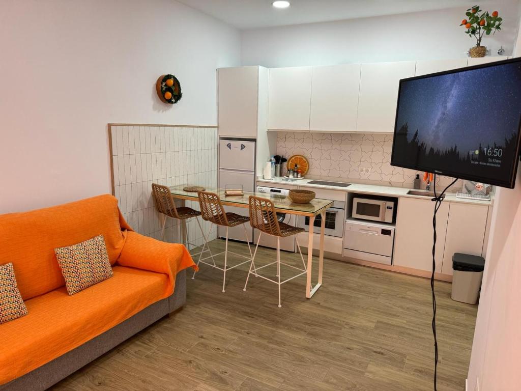 a living room with an orange couch and a kitchen at Orange Suite by Alhaurín Loft City Center in Alhaurín de la Torre