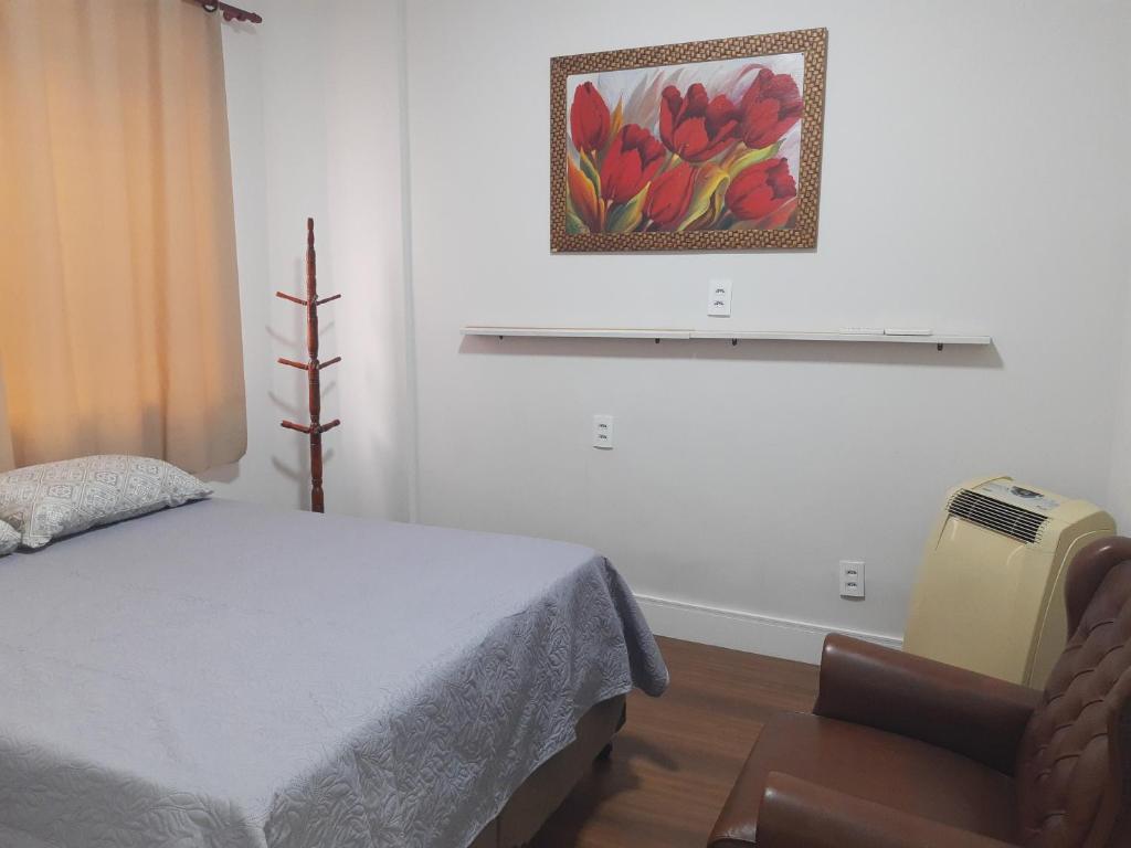 a bedroom with a bed and a chair and a picture at Apart Prime in Campinas