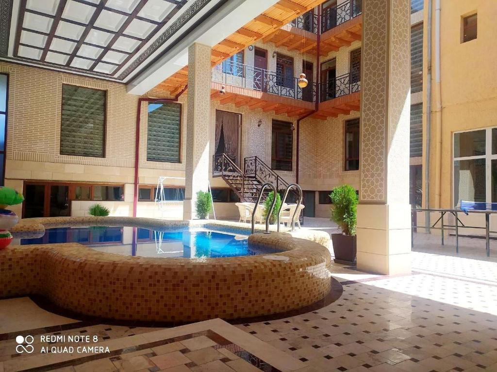a large building with a swimming pool in a courtyard at Hotel Shams in Bukhara