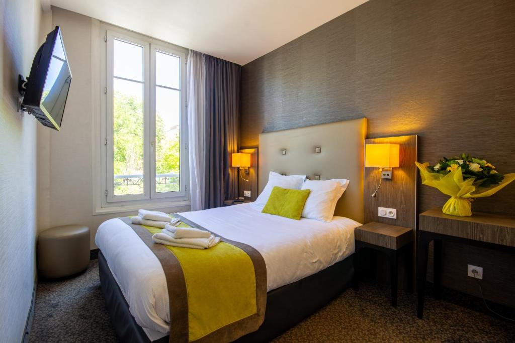 een hotelkamer met een bed en een televisie bij Hotel de la Gare Troyes Centre in Troyes