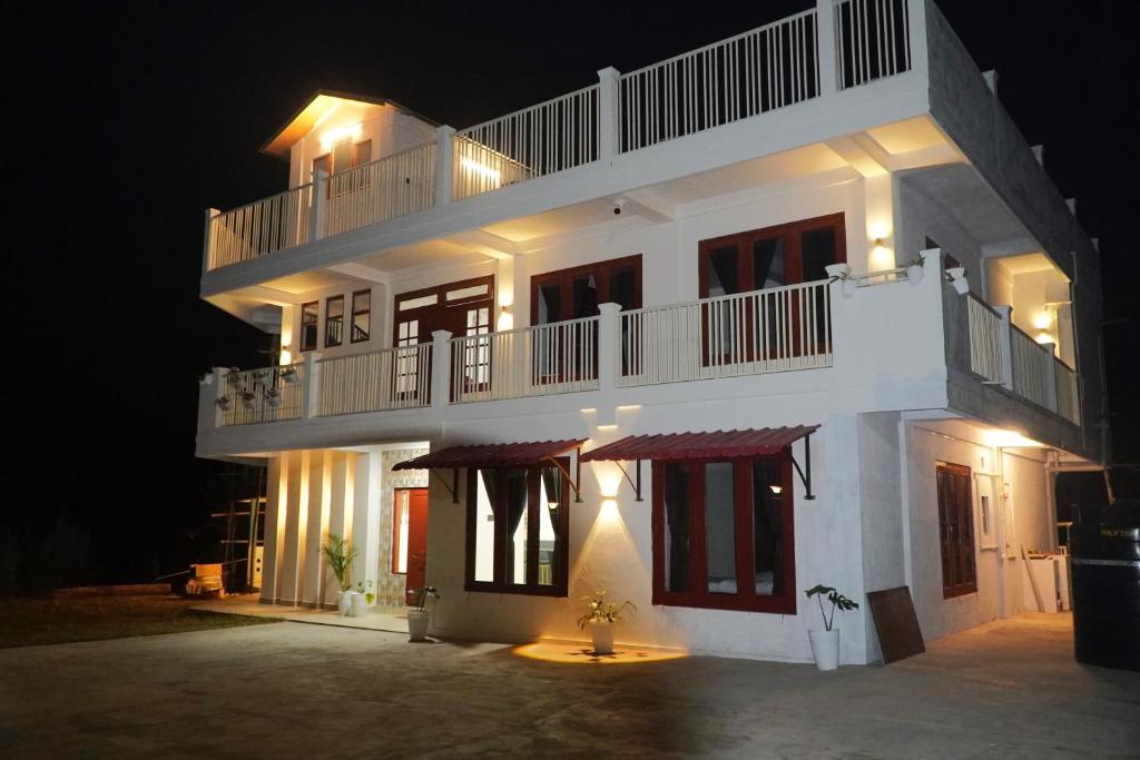 Un grand bâtiment blanc avec balcon est disponible la nuit. dans l'établissement ROYALTY GLOBAL HOMESTAY, à Shillong