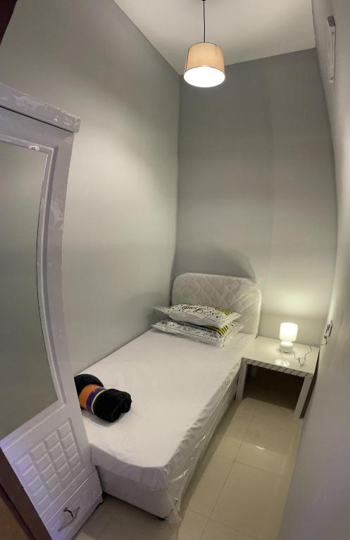um pequeno quarto branco com uma cama e um candeeiro em Pharaohs Inn MOE Hostel em Dubai