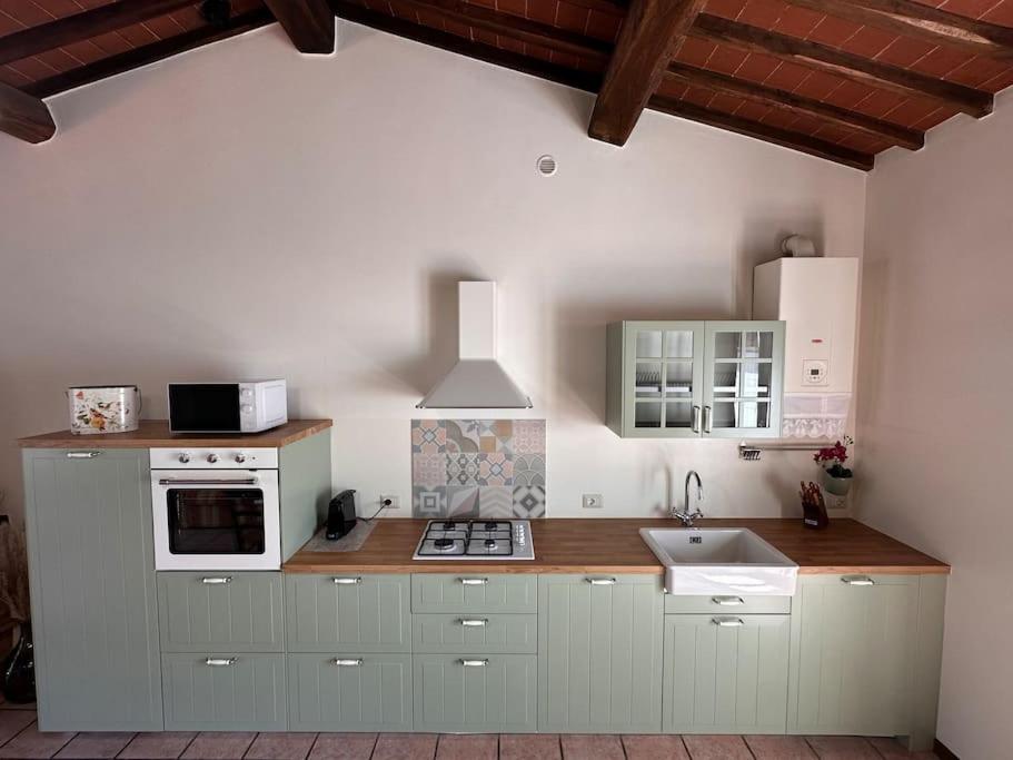 Una cocina con gabinetes blancos y un horno de estufa. en Casa il Cipresso, en Castelnuovo Berardenga