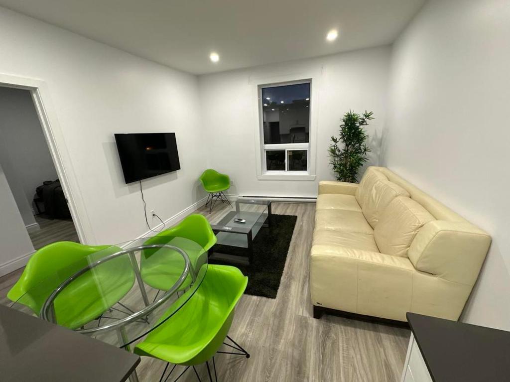 uma sala de estar com um sofá branco e cadeiras verdes em Appartement 2 chambres - 202 em Montreal