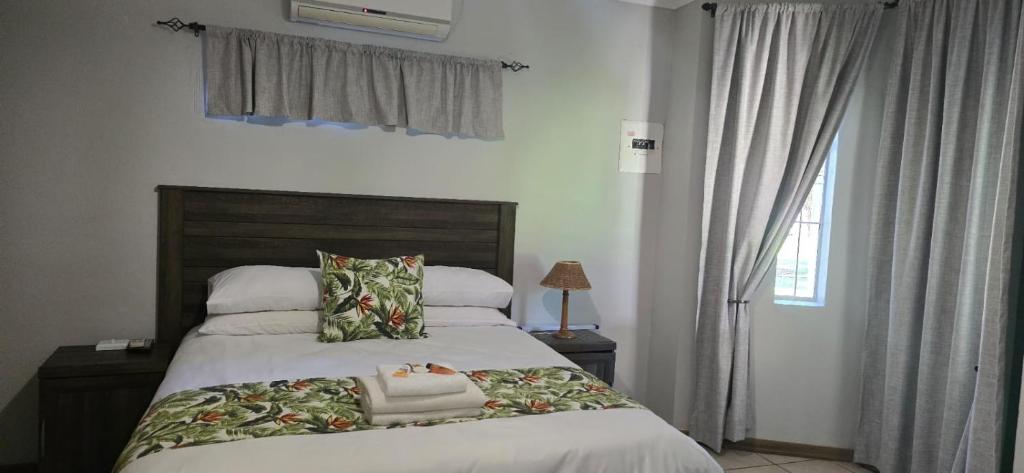 a bedroom with a large bed and a window at Grey lourie Guesthouse in Zeerust