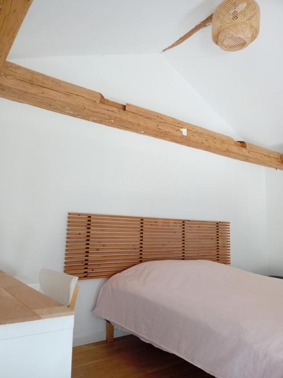 1 dormitorio con cama blanca y cabecero de madera en Chambre de charme, en Cuers