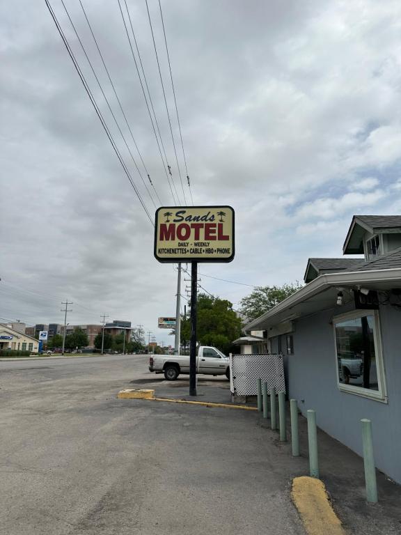 a sign for a motel in a parking lot at Sands Motel in San Antonio