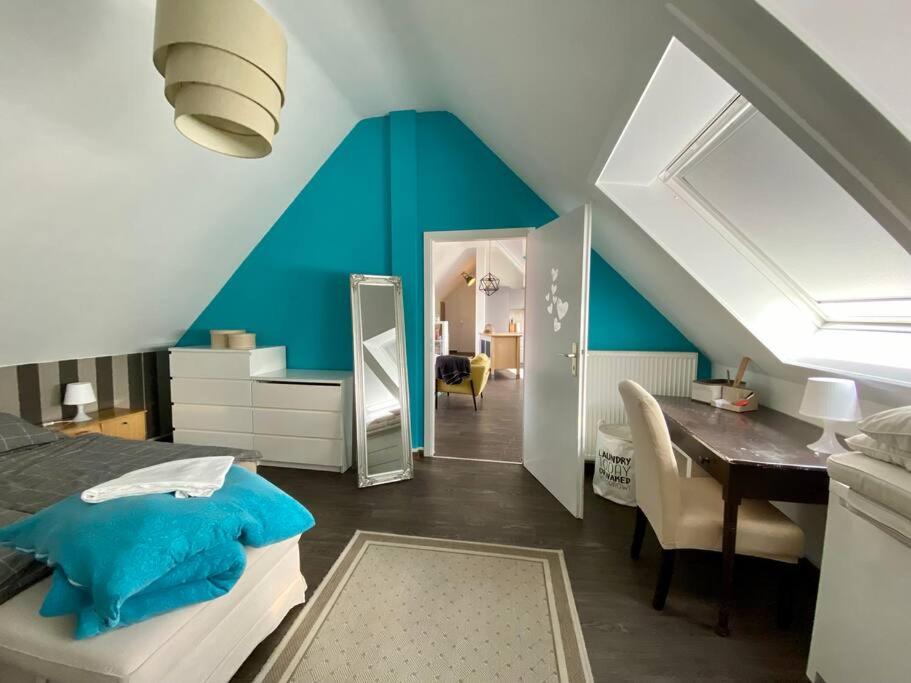 a bedroom with a blue wall and a table and a mirror at Light flow stylish attic house. m. balcony in Rastatt