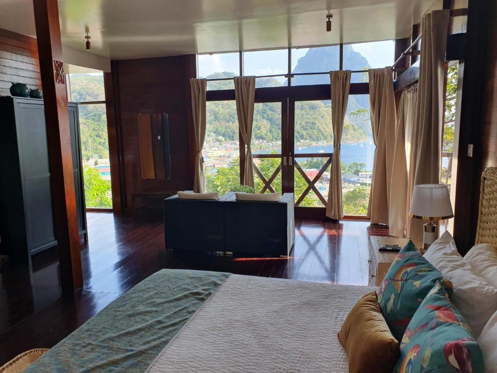 a living room with a bed and large windows at Green Fig Resort & Spa in Soufrière