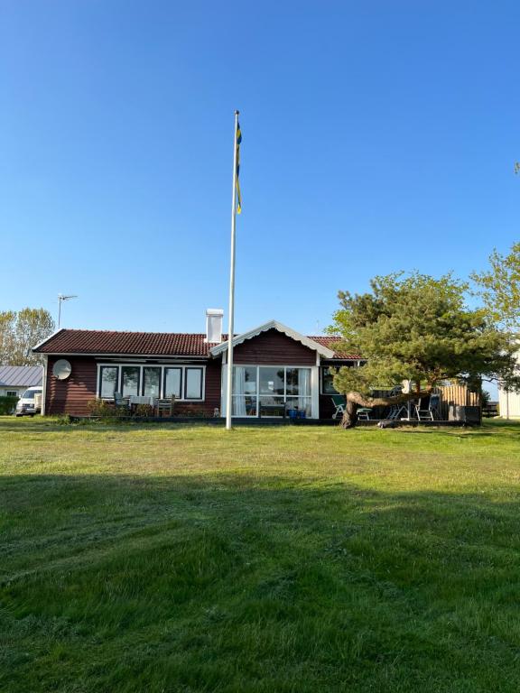 a house with a pole in front of a yard at Stuga i Björkäng med havsutsikt! in Tvååker