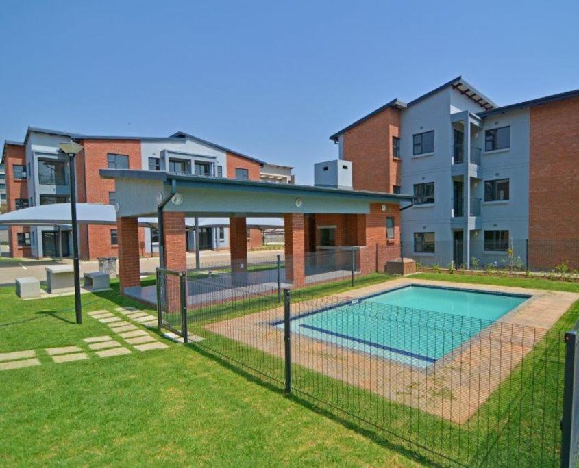 a swimming pool in a yard in front of a building at Saffron Place @ 2bed Apt Midrand in Midrand