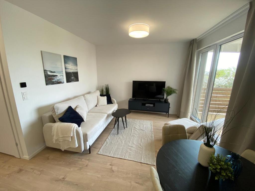 a living room with a white couch and a tv at Lazur Seven in Gdańsk