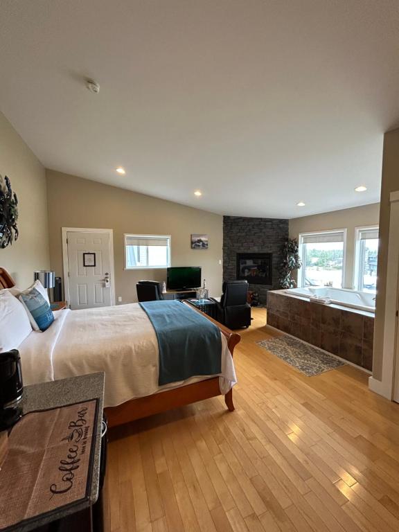 ein großes Schlafzimmer mit einem großen Bett und einem Kamin in der Unterkunft Pacific Rim Guest Lodge - Adults Only in Ucluelet