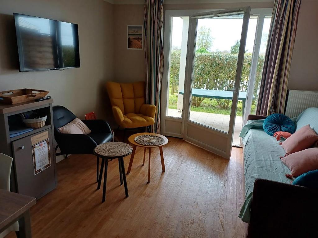 uma sala de estar com um sofá e cadeiras e uma porta de vidro deslizante em Le 501 F2 de plain-pied avec terrasse em Courseulles-sur-Mer