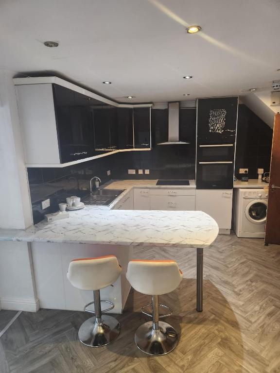 a kitchen with a marble counter and two bar stools at Thorogood house in Dagenham