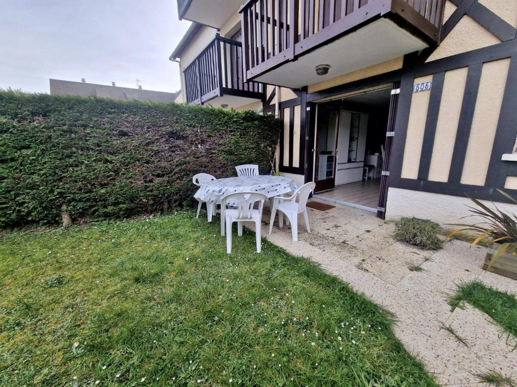 une table et des chaises dans l'herbe à l'extérieur d'une maison dans l'établissement Rez-de-jardin près de la mer, à Cabourg