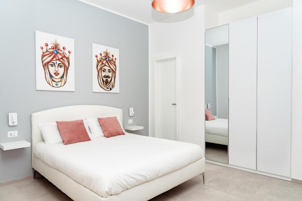 a white bedroom with a bed and a mirror at La maison de tante Rosa in Siracusa