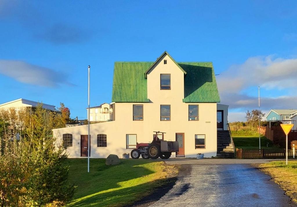 ein großes weißes Haus mit grünem Dach in der Unterkunft Ásgarður in Hrísey