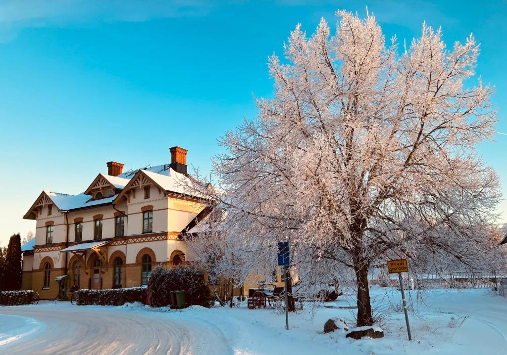 a large house with a tree in the snow at Stationshus apartment in Hallstahammar