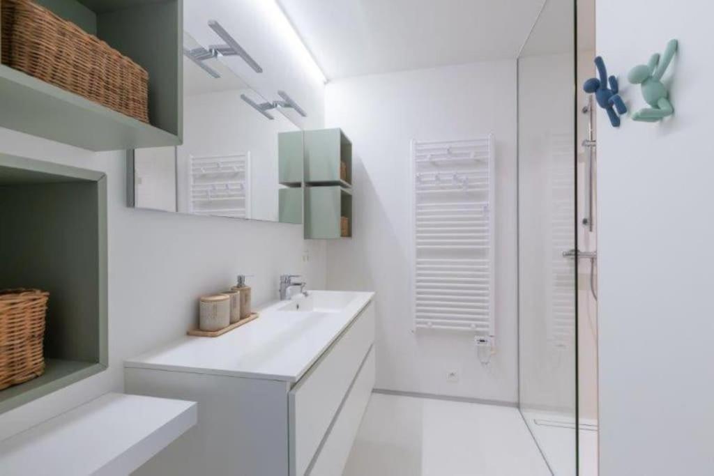 オーステンデにあるLuxe d’Oの洗面台とシャワー付きの白いバスルーム