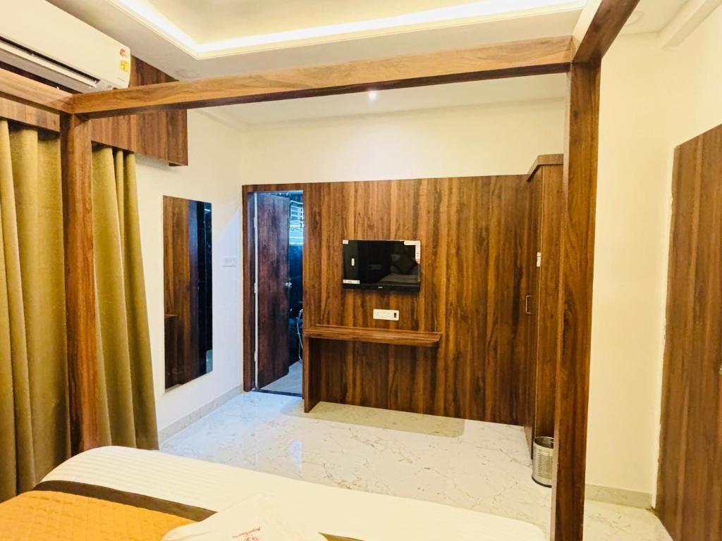 a bedroom with wooden walls and a tv on a wall at Airport Hotel Relax Inn in Nagpur