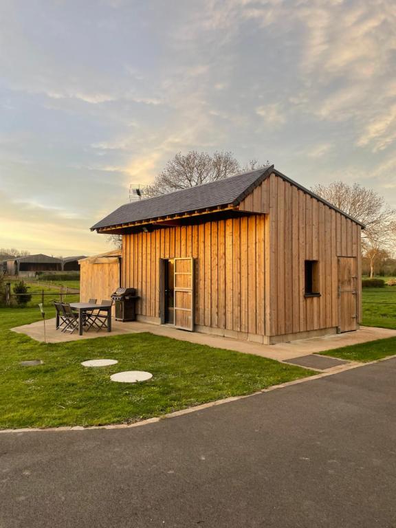 - un bâtiment en bois avec une table de pique-nique dans un champ dans l'établissement la clef des champs, à Ryes