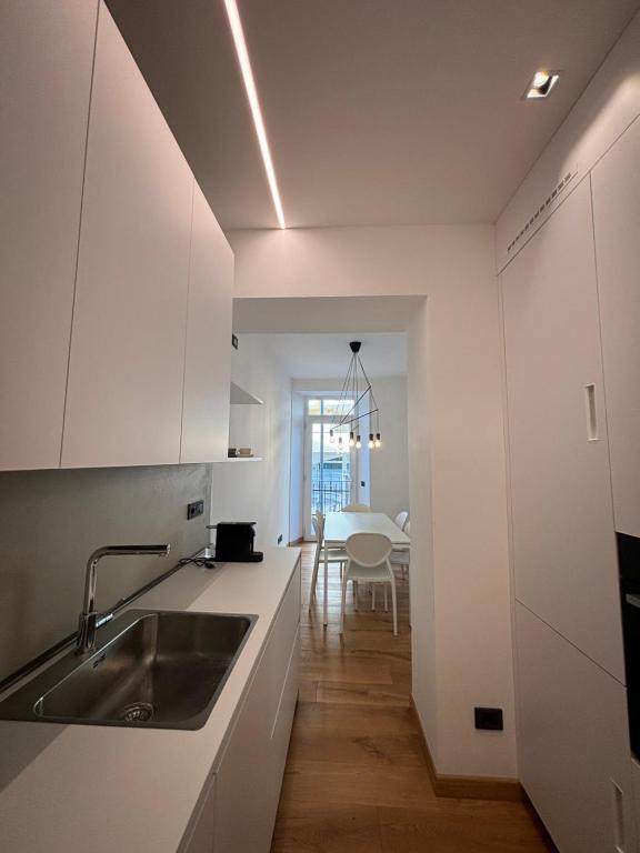 a kitchen with white cabinets and a sink and a table at Residenza la Torretta in Domodossola