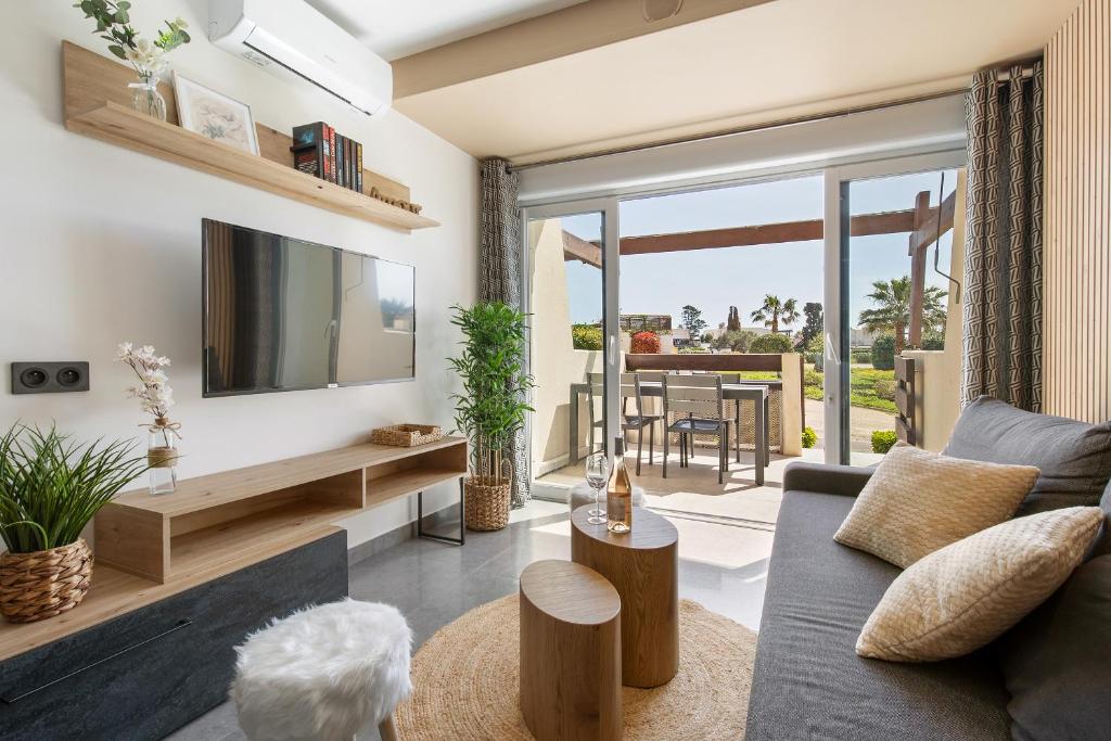 un salon avec un canapé et une télévision dans l'établissement Le Jardin des Sens naturiste, au Cap d'Agde