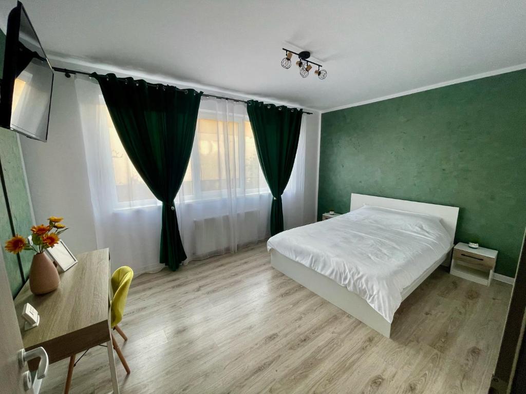 een slaapkamer met een wit bed en een groene muur bij Greenlight Studio by DAT Apartments in Cluj-Napoca