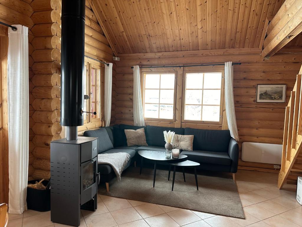 Una sala de estar con un sofá y una estufa. en Koslig tømmerhytte, en Kilpisjärvi