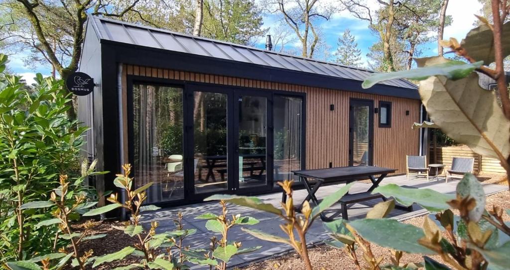a small cabin with glass doors and a patio at Boslodge Bosmus - 4 personen - NIEUW in Nunspeet